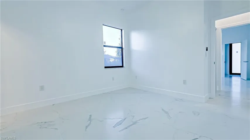 Spare room featuring baseboards and light marble finish flooring
