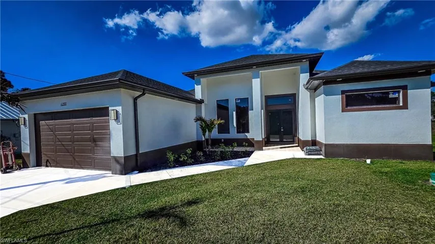 Prairie-style home with a front lawn, french doors, a garage, stucco siding, and driveway