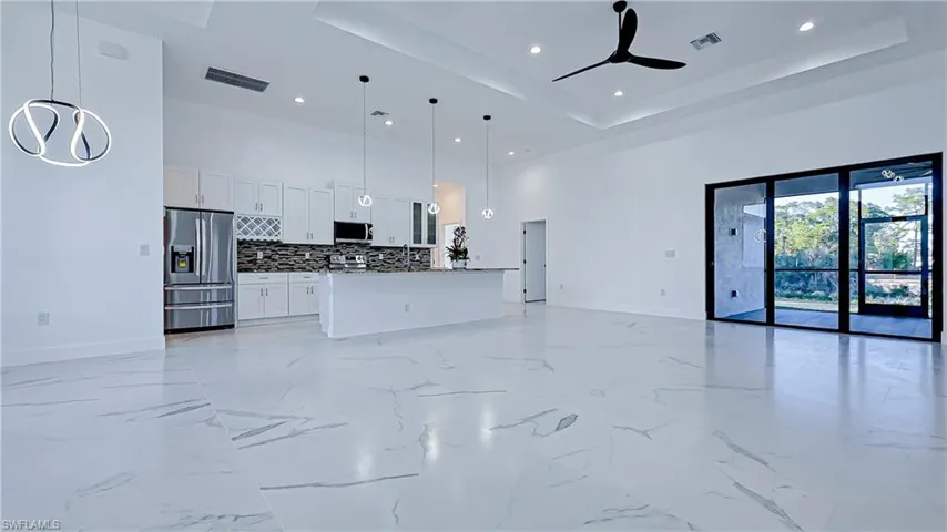 Unfurnished living room with a high tray ceiling, recessed lighting, and ceiling fan
