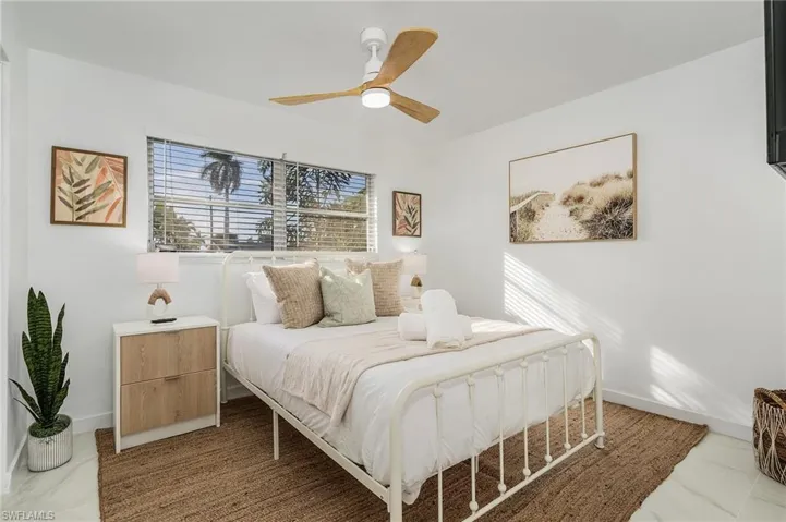 Bedroom with marble look tiles, baseboards, and ceiling fan