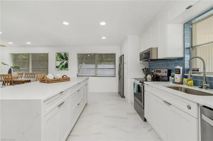 Kitchen with stainless steel appliances, a sink, recessed lighting, a center island, and white cabinetry