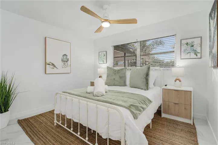 Bedroom featuring light marble finish flooring, ceiling fan, and baseboards