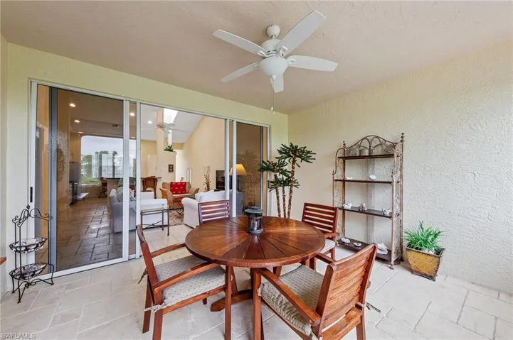 Dining area featuring a textured wall, ceiling fan, stone tile floors, and a textured ceiling