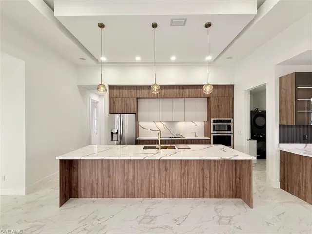 Kitchen with appliances with stainless steel finishes, modern cabinets, brown cabinets, light marble finish floors, and recessed lighting