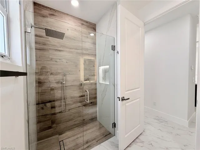 Full bathroom with marble look tile flooring, a marble finish shower, and recessed lighting