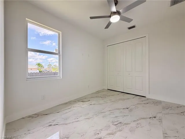 Unfurnished bedroom with light marble finish floors, a closet, and ceiling fan