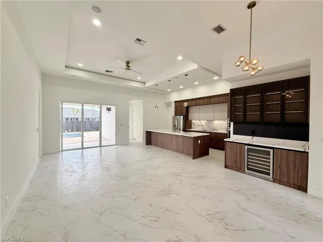 Kitchen with wine cooler, open floor plan, modern cabinets, a kitchen island with sink, and recessed lighting