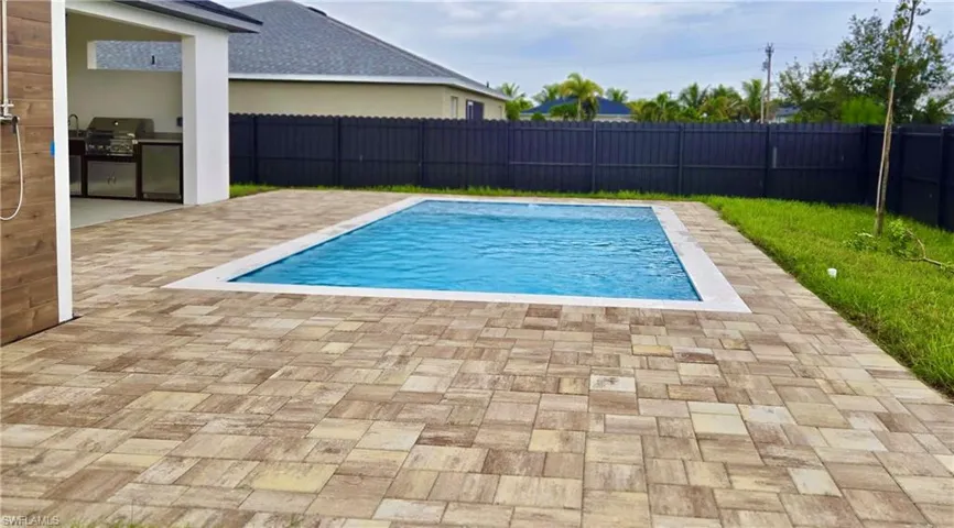 View of swimming pool featuring a fenced backyard, a patio, and area for grilling