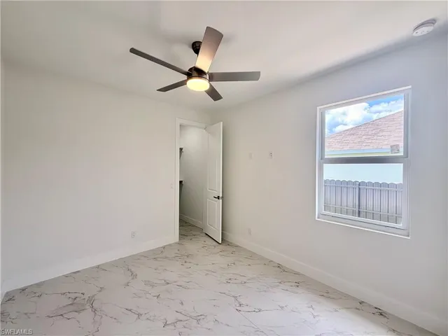Spare room with light marble finish floors, a ceiling fan, and a smoke detector