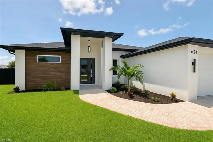 View of front of property with a front yard, stucco siding, and a garage