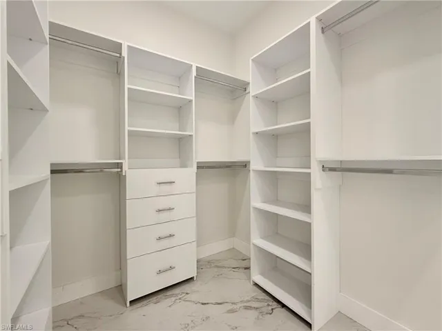 Spacious closet featuring light marble finish flooring