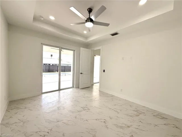 Spare room featuring recessed lighting, a raised ceiling, a ceiling fan, and light marble finish floors