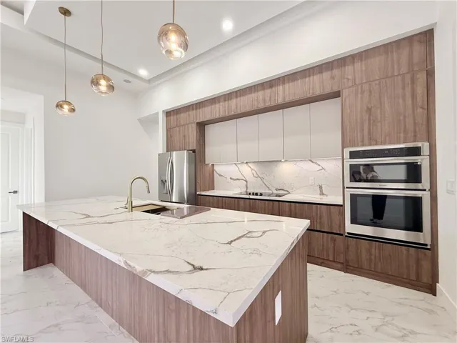 Kitchen with modern cabinets, stainless steel appliances, light marble finish floors, decorative backsplash, and recessed lighting