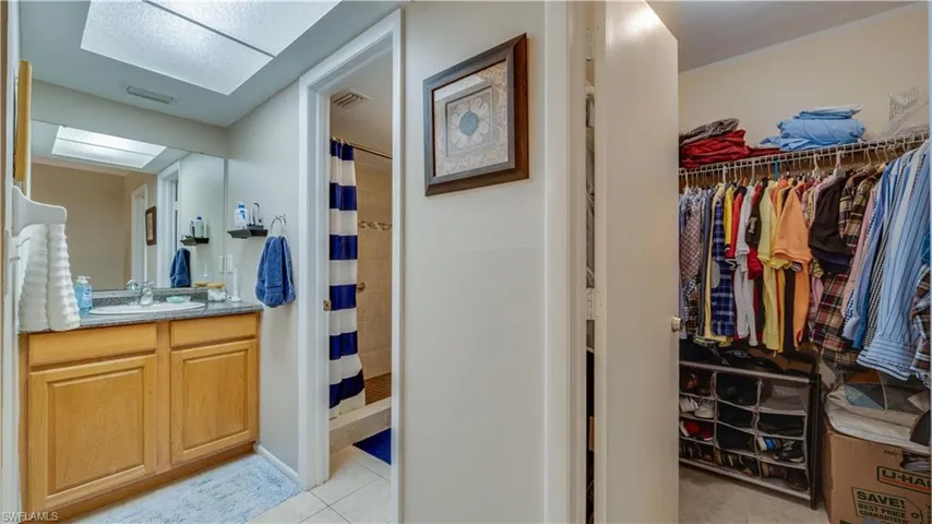 Full bath with vanity, a stall shower, light tile patterned floors, and a spacious closet