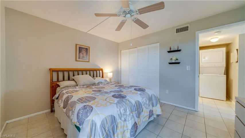 Bedroom featuring stacked washer / drying machine, a closet, a ceiling fan, and light tile patterned floors