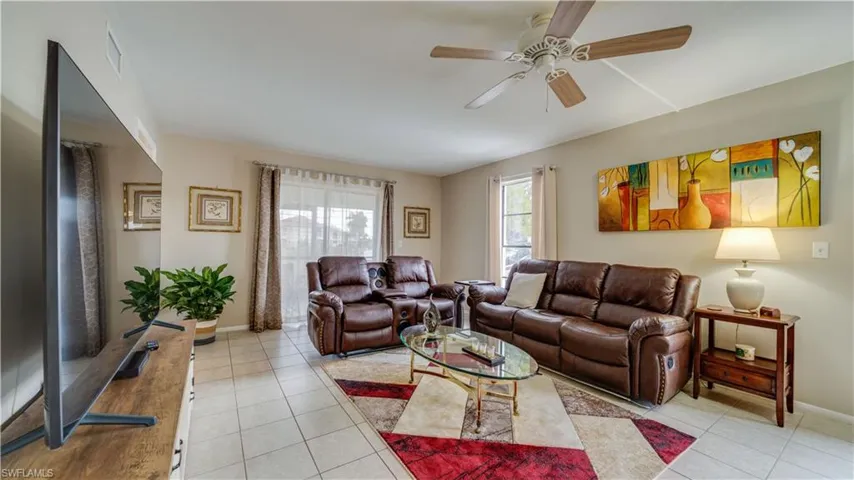 Living area featuring light tile patterned floors and ceiling fan