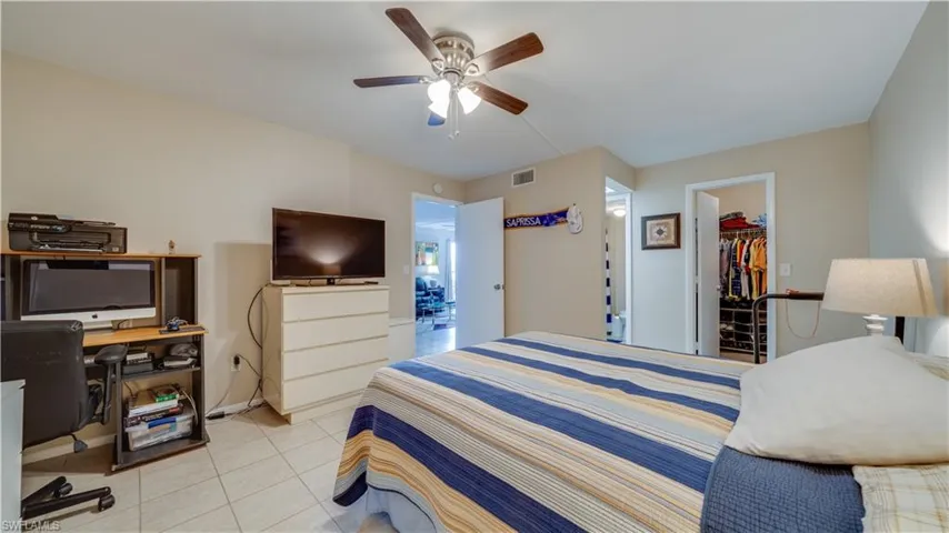 Bedroom with a walk in closet, light tile patterned floors, an office area, and ceiling fan