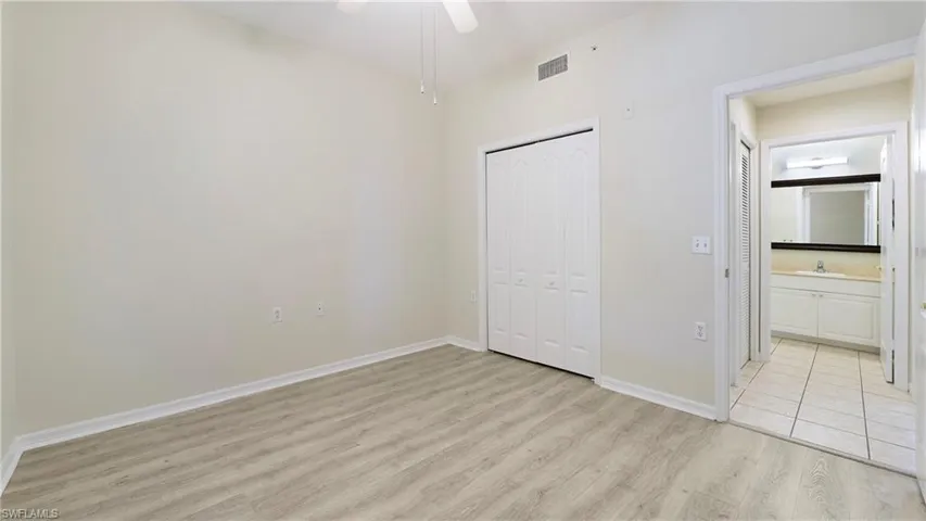 Unfurnished bedroom featuring light wood-style flooring, a closet, a ceiling fan, and ensuite bathroom