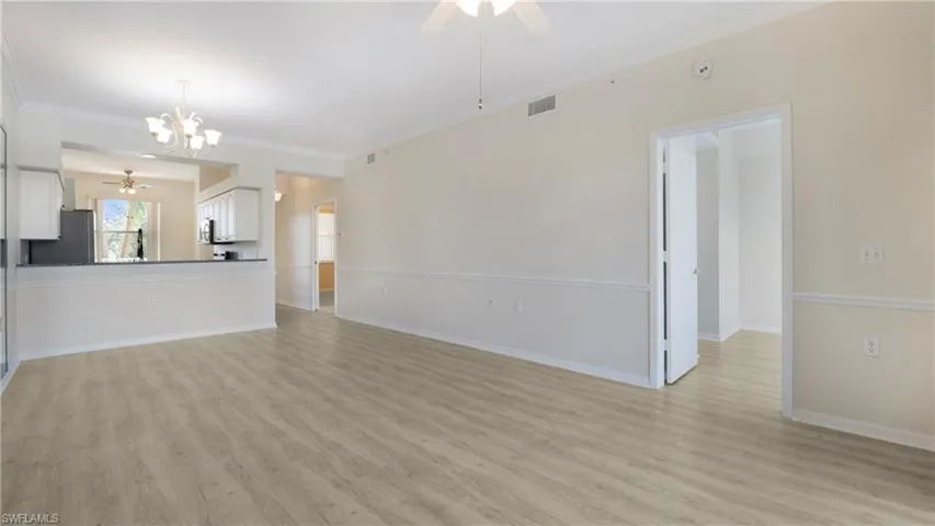 Unfurnished living room featuring a ceiling fan, light wood-style floors, a chandelier, and ornamental molding