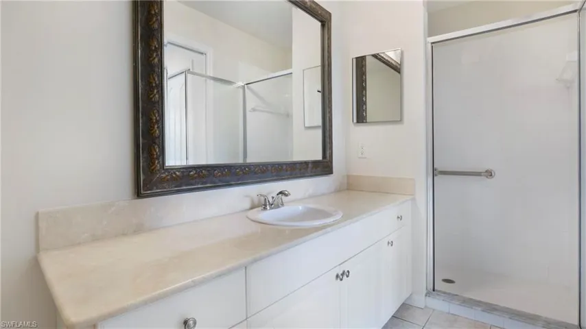 Bathroom featuring a stall shower, vanity, and light tile patterned flooring