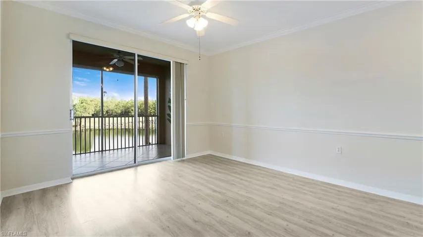 Empty room featuring light wood-style flooring, ornamental molding, and a ceiling fan