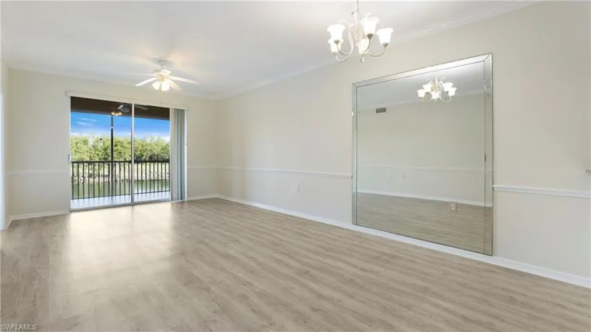 Empty room featuring wood finished floors, ceiling fan, ornamental molding, and a chandelier