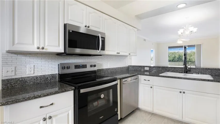 Kitchen featuring appliances with stainless steel finishes, white cabinets, tasteful backsplash, pendant lighting, and crown molding
