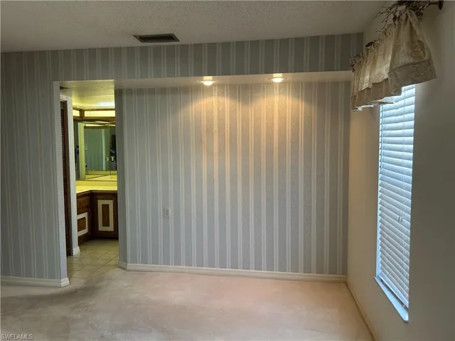Primary suite featuring light carpet and a textured ceiling