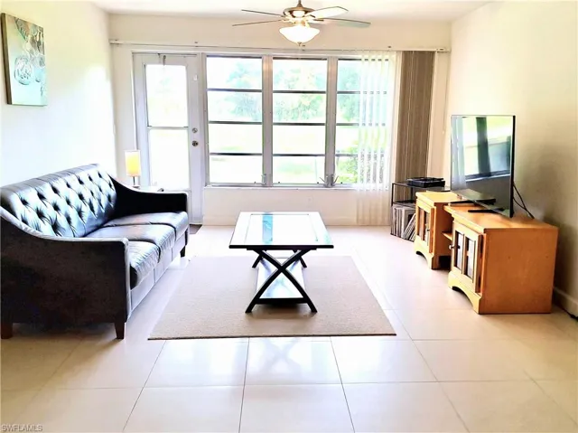 Living room with ceiling fan, light tile patterned flooring, and a wealth of natural light