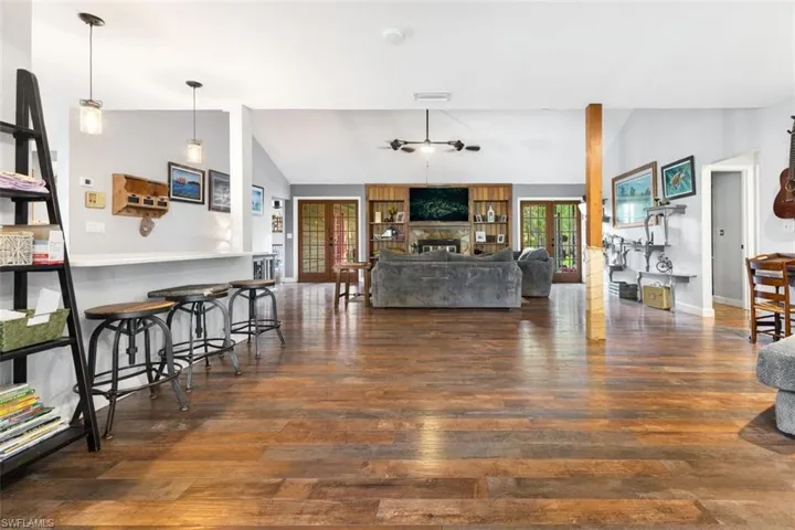 Living room with vaulted ceiling, wood finished floors, a ceiling fan, baseboards, and a fireplace