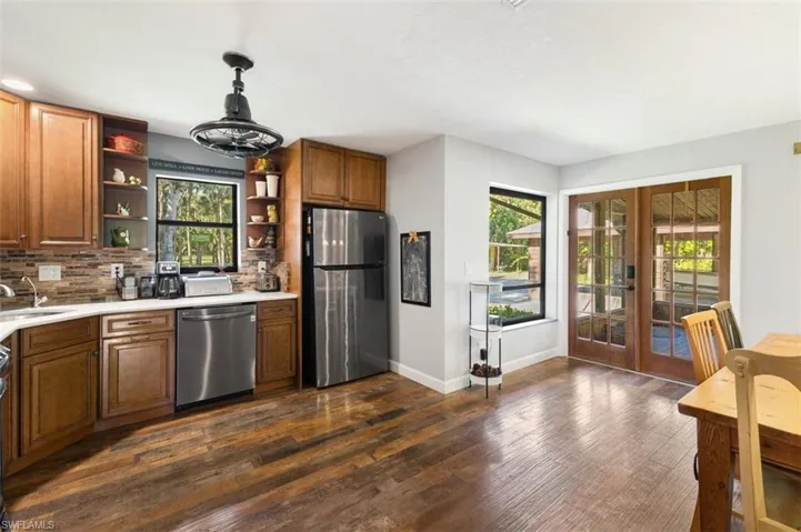 Kitchen with appliances with stainless steel finishes, open shelves, french doors, tasteful backsplash, and plenty of natural light