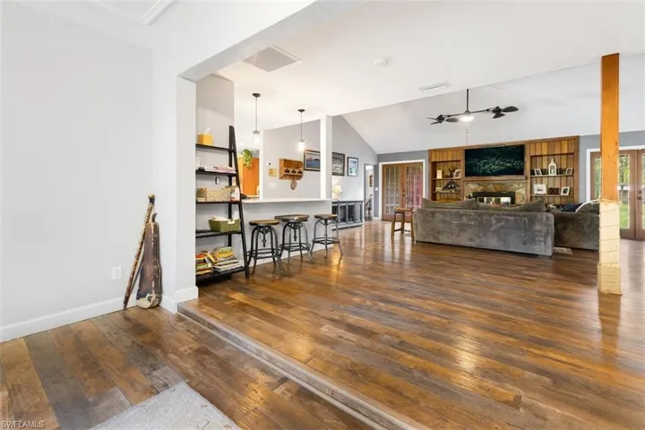 Living room with vaulted ceiling, ceiling fan, hardwood / wood-style floors, a fireplace, and baseboards