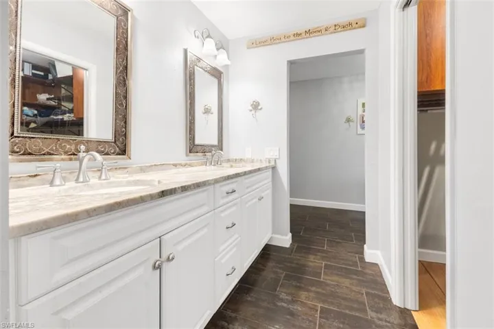 Full bathroom with wood finished floors, double vanity, and baseboards