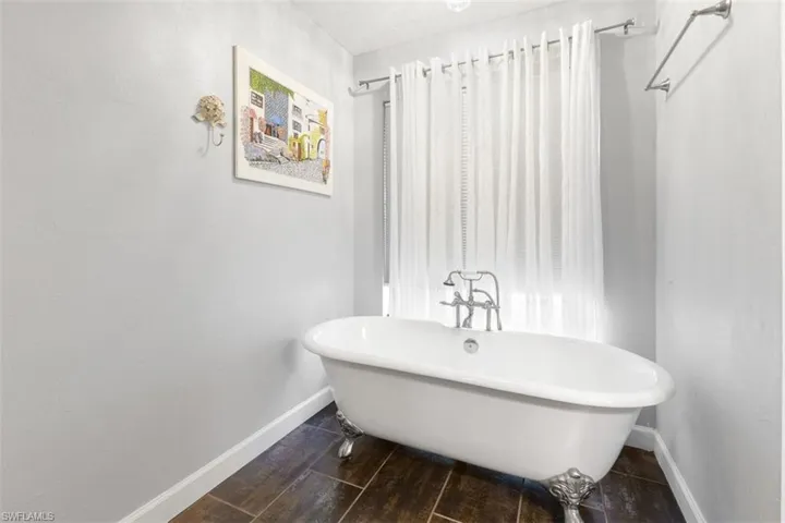 Full bathroom with baseboards, a soaking tub, and wood finished floors