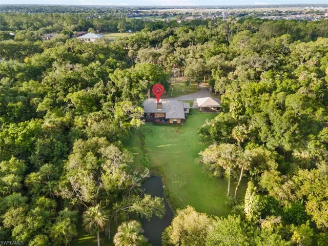 Aerial view of property and surrounding area with a forest