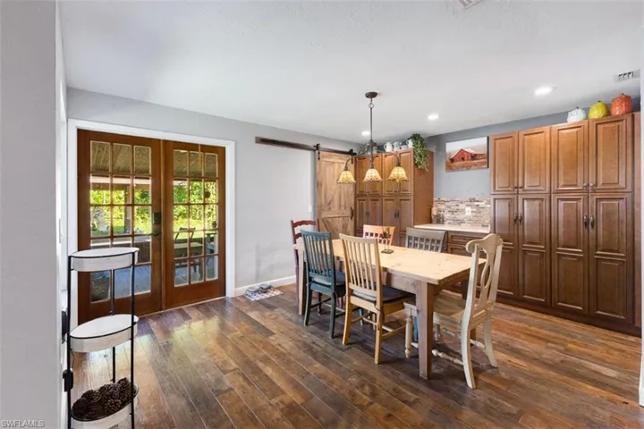 Dining space featuring a barn door, dark wood-style flooring, baseboards, recessed lighting, and french doors