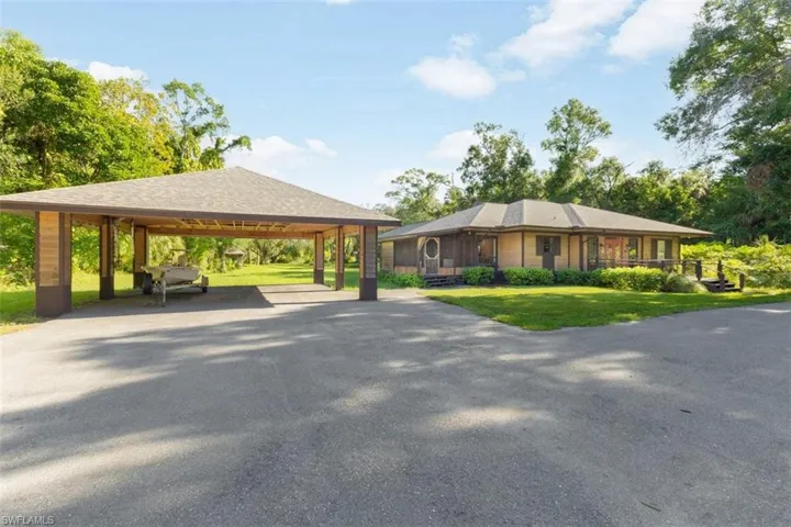 View of front of house with driveway, a front lawn, and a carport