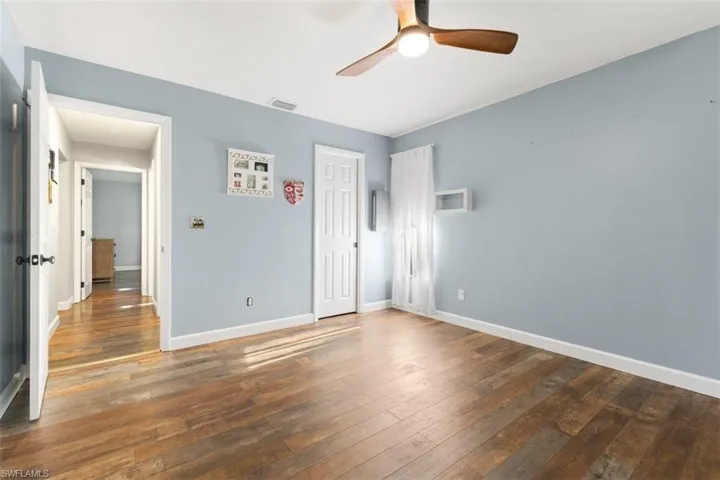 Unfurnished bedroom with hardwood / wood-style flooring, baseboards, a ceiling fan, and a closet