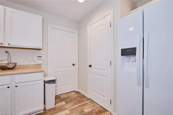 Kitchen with white fridge with ice dispenser, white cabinets, and light hardwood / wood-style flooring