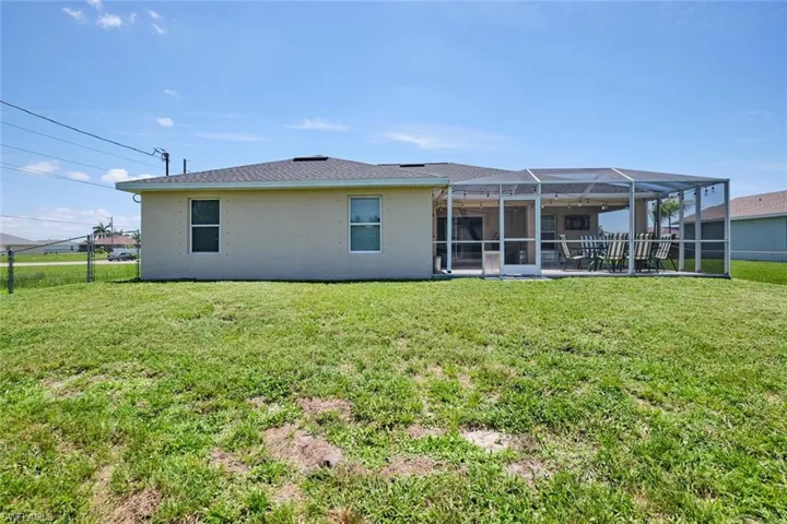 Back of house with a yard and a lanai