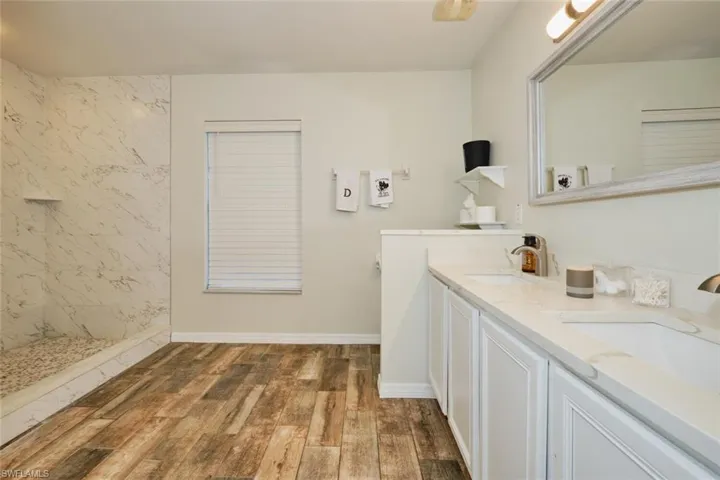 Bathroom featuring tiled shower, dual vanities