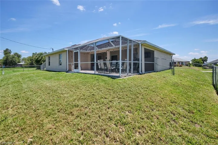 Rear view of house featuring a lawn, a lanai, and a patio