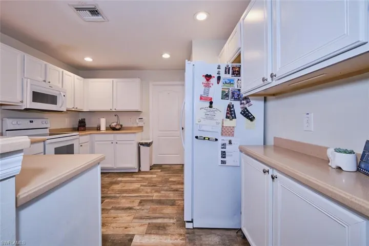 Kitchen featuring wood-type flooring, white cabinetry, and white appliances