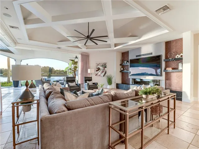 Living room with coffered ceiling, a ceiling fan, beam ceiling, and light tile patterned flooring