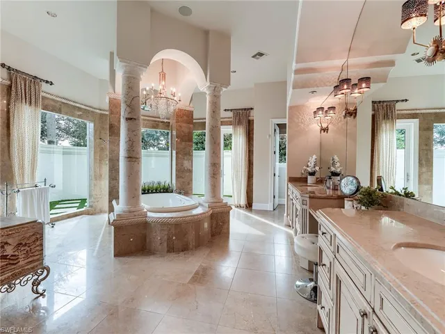 Full bath featuring a chandelier, a garden tub, ornate columns, and vanity