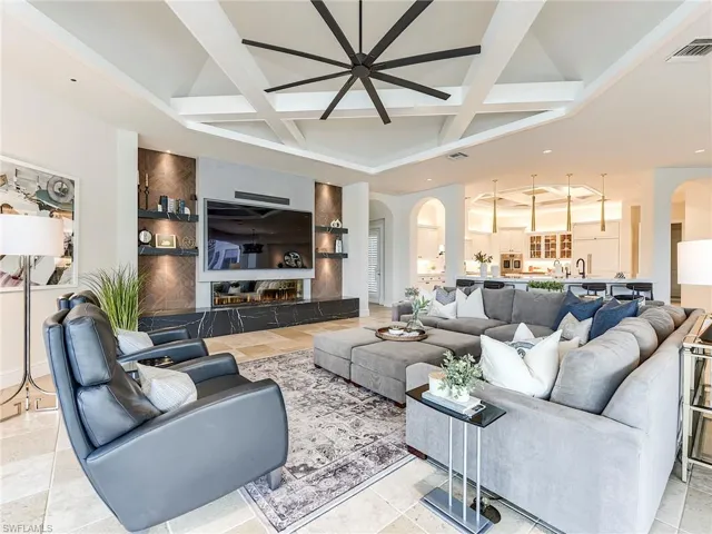 Tiled living area with arched walkways, coffered ceiling, and beam ceiling