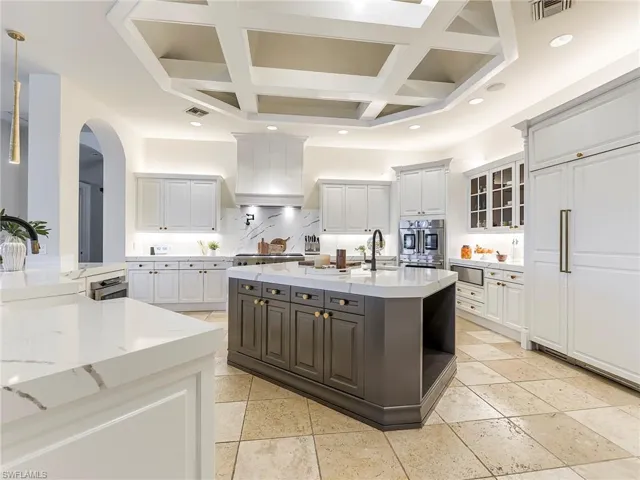 Kitchen featuring an island with sink, light stone countertops, white cabinetry, coffered ceiling, and recessed lighting