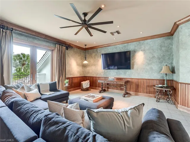 Upstairs media Room featuring wainscoting, wooden walls, crown molding, tile patterned floors, and ceiling fan