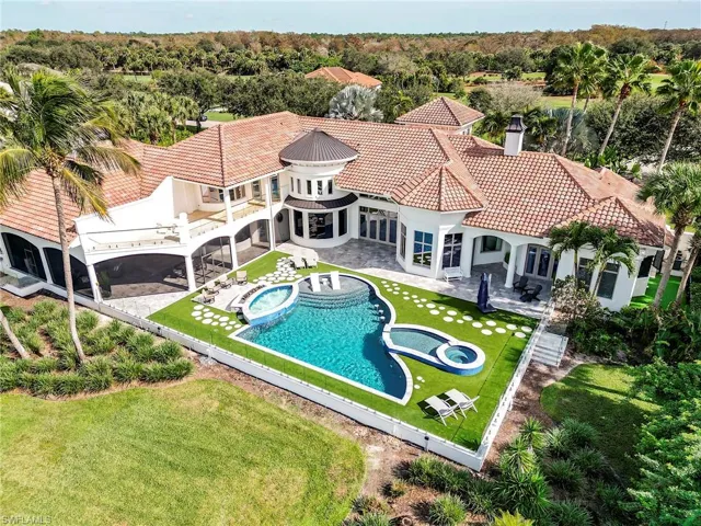 Rear view of property featuring a patio area, a pool with connected hot tub, a tiled roof, and a chimney