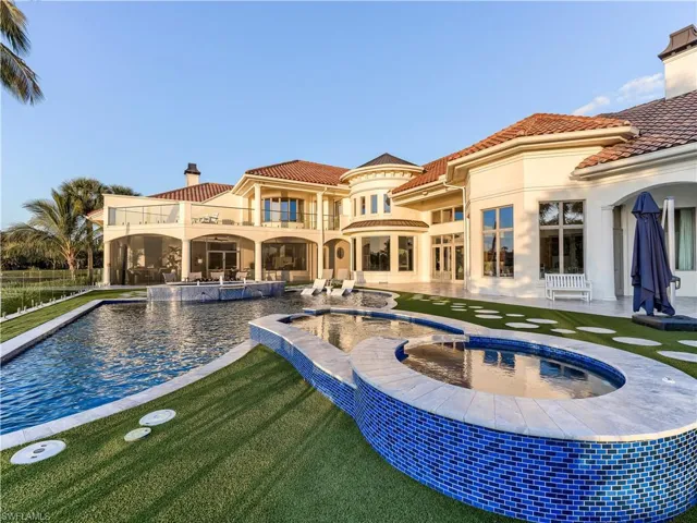 View of pool featuring a balcony, a pool with connected hot tub, a patio area, and a lawn